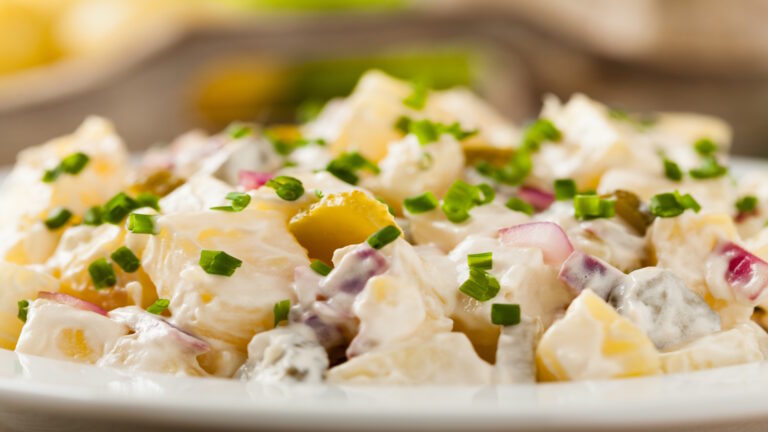 Traditioneller deutscher Kartoffelsalat mit Gurke, Zwiebel und Mayonnaise.