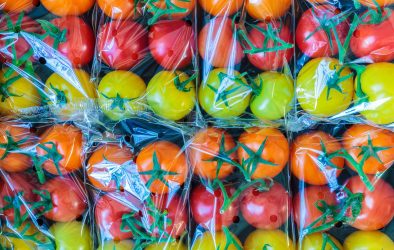 Display of fresh plastic wrapped yellow, orange and red cherry tomatoes